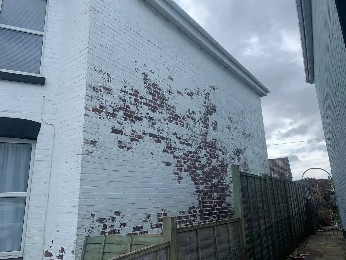 Peeling paint on a brick wall before redecoration in Port Isaac